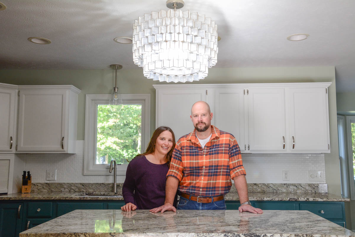 Erin and Eric in painted kitchen with white cabinets and green lower cabinets.