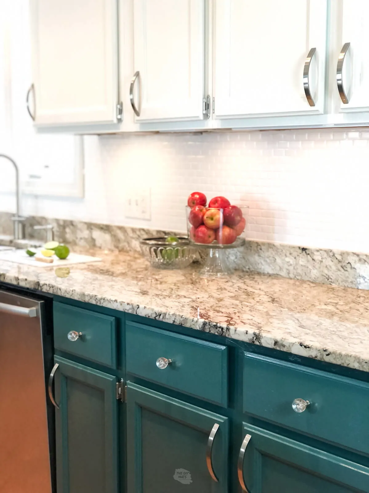 two toned painted blue green kitchen cabinets with white upper cabinets and red apples on counter.